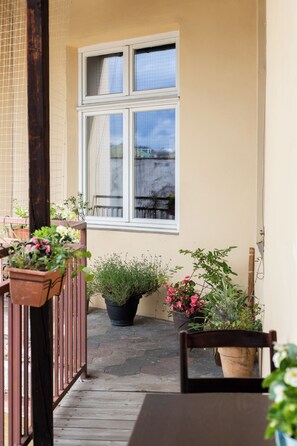 A balcony with potted plants, a window, and a wooden table. - Native Apartments Łazarza 3 (Kraków)