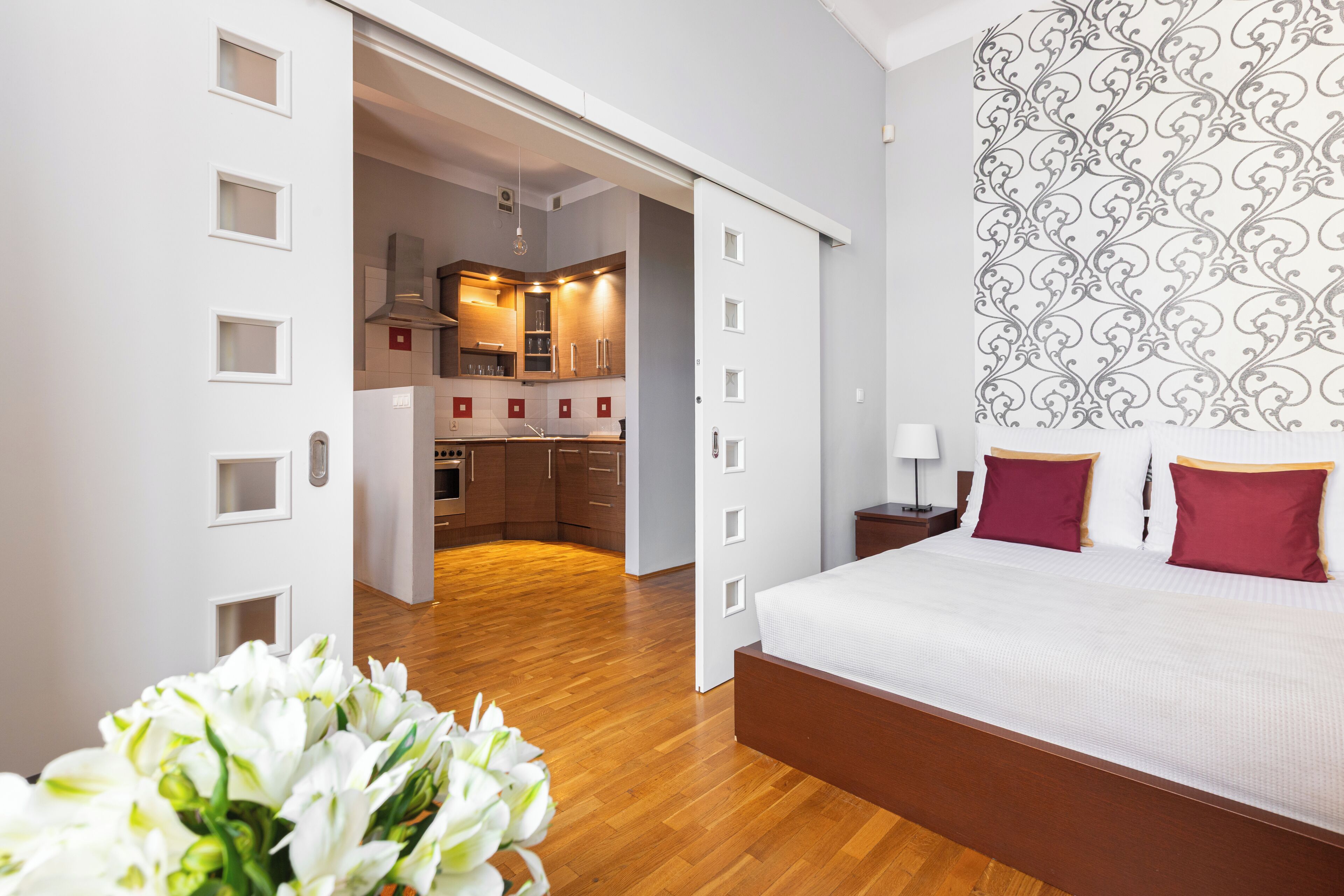 A bedroom with a large bed, a nightstand, and a wall with a decorative pattern.