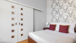 Et soveværelse med en seng, en garderobe med flere døre, et natbord og en tapetvæg.