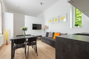 A modern living space with a dining area, sofa, and a flat-screen TV. - Native Apartments Łazarza 3 (Kraków)