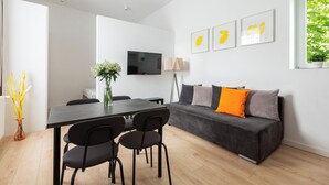 En moderne stue med sofa, spisebord med stole, et fladskærms-tv og billeder i rammer på væggen.