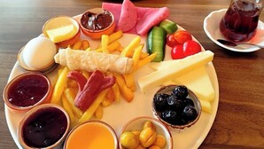A table with a variety of food items including cheese, meats, and fruits, along with small bowls of condiments. - ROZA TAKSIM  (Istanbul)