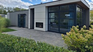 Un bâtiment moderne doté de grandes fenêtres, d’un toit plat et d’un espace d’entrée pavé.