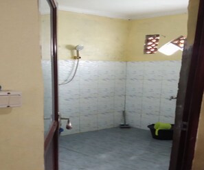 Ein kleines, abgeschlossenes Badezimmer mit Dusche, gefliesten Wänden und einer sichtbaren Leuchte.
