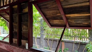 Una estructura de madera con vistas a un muro de ladrillo y follaje exterior.