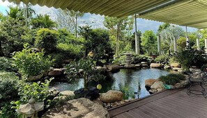 A serene garden with a pond, rocks, and a wooden deck.