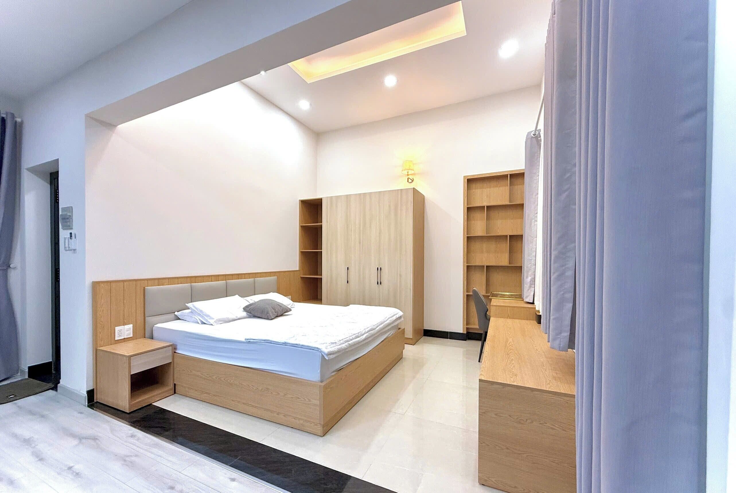 Una camera da letto moderna con un letto, comodini in legno, un'armadio e una scrivania.