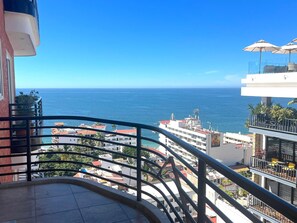 Ein Balkon mit Meerblick, einem Geländer und einem mehrstöckigen Gebäude.