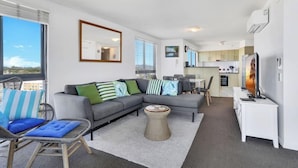 Un appartement moderne comprenant un espace de vie, une cuisine et un balcon.