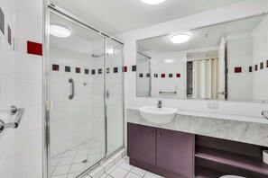 A modern bathroom with a glass shower enclosure, a white sink, and a large mirror. - Amazing Ocean Views from Unit 87-Catalina-II (Maroochydore)
