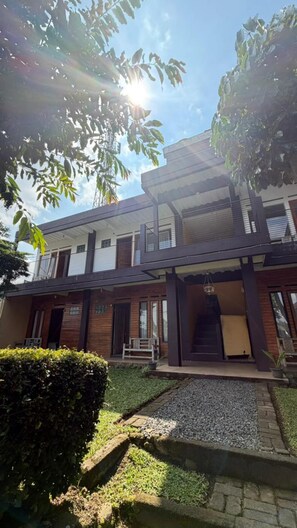 A modern two-story building with a flat roof, a balcony on the upper floor, and a small front porch. - Jayagiri Inn (Lembang)