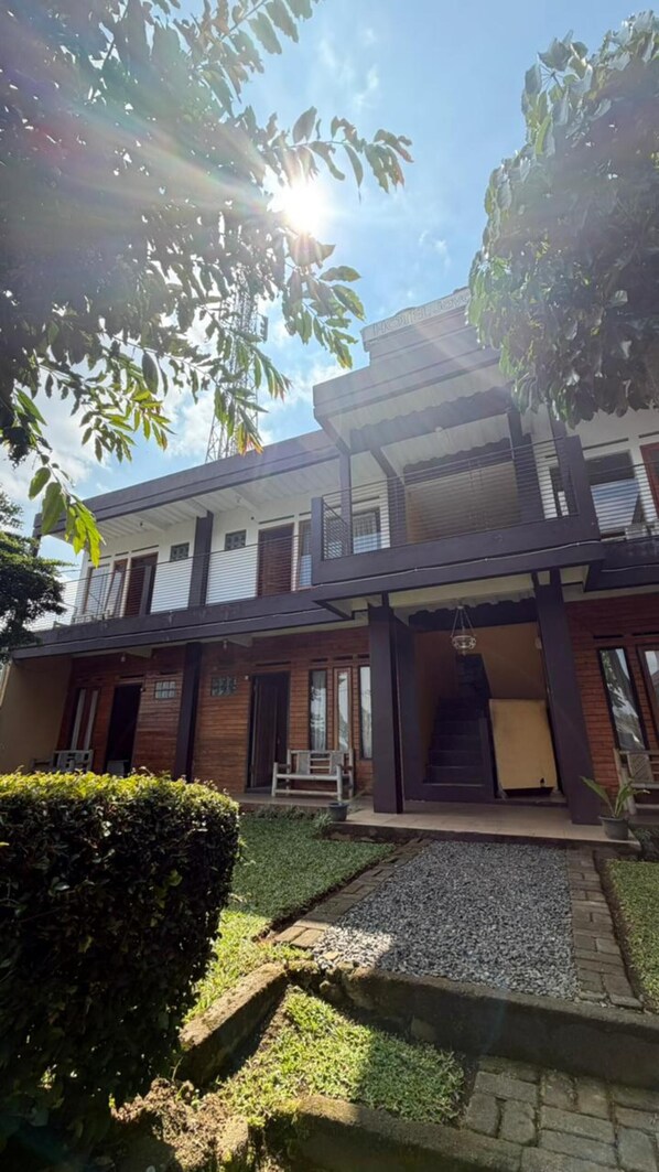 A modern two-story building with a flat roof, a balcony on the upper floor, and a small front porch.