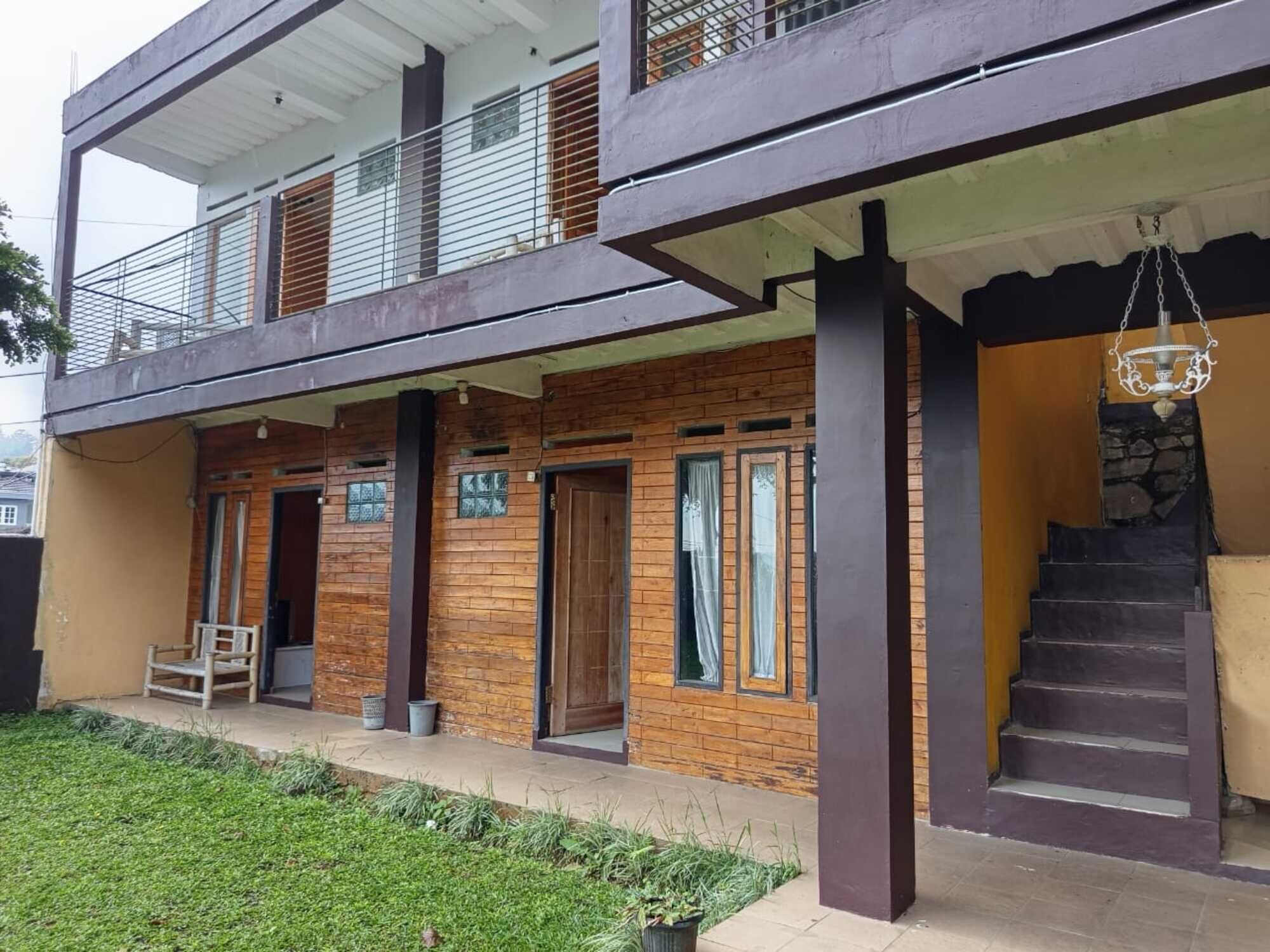 A modern two-story building with a balcony, a staircase, and a hanging light fixture.