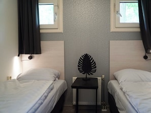 Ein Zimmer mit zwei Betten, einer Heizung und einem Wandventilator.