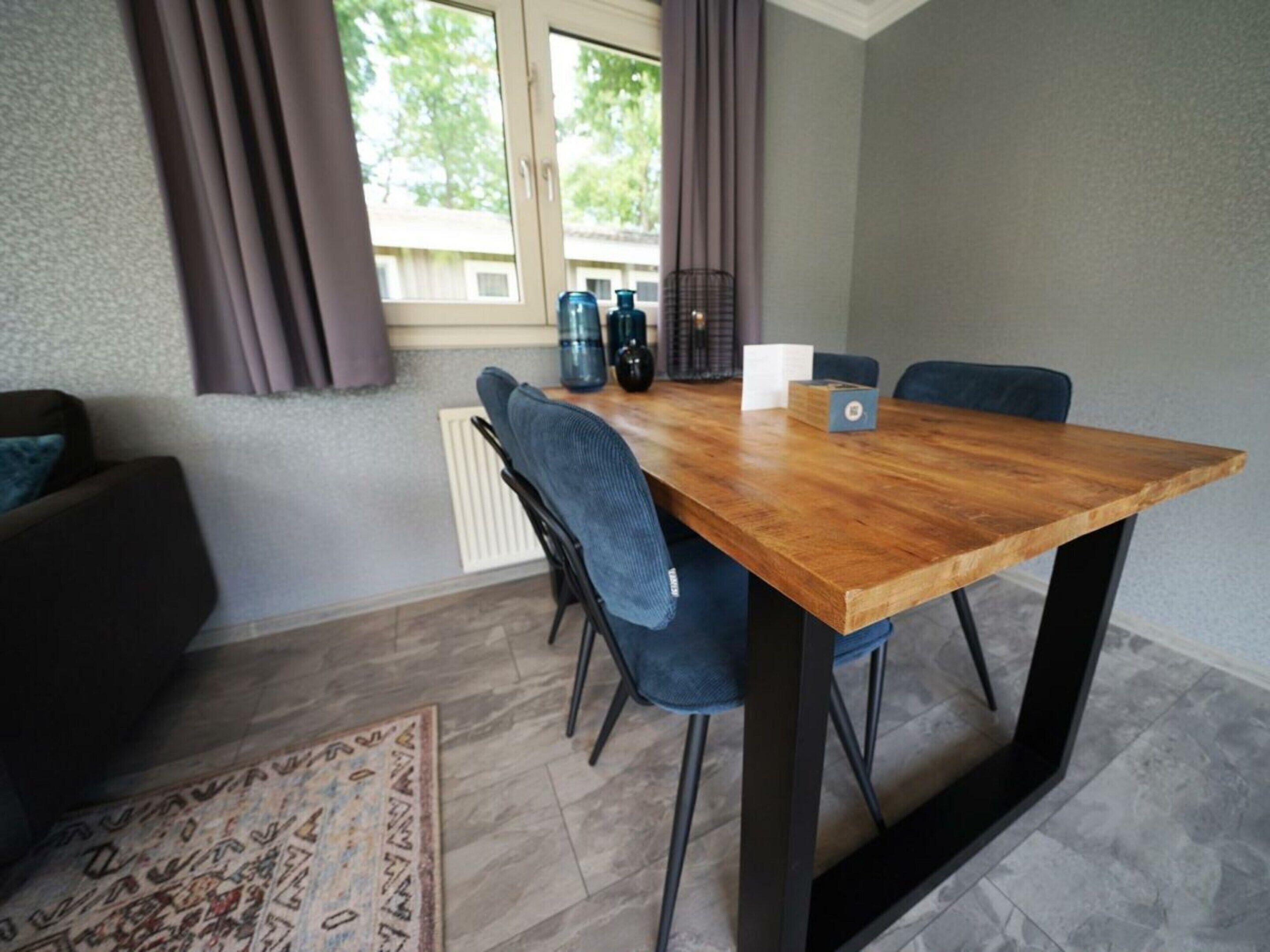 Ein Essbereich mit einem Holztisch, vier Stühlen, einer Kaffeemaschine und einem Heizkörper.