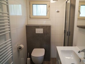 Ein Badezimmer mit Toilette, Waschbecken, Fenster und Dusche.