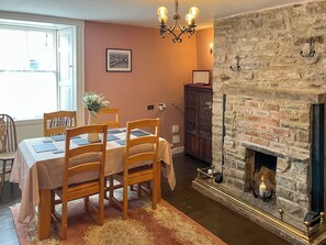 Ein Esszimmer mit Tisch für vier Personen, Kamin und Steinwand.