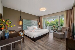 Habitación de hotel con una cama grande, un escritorio, una silla, un televisor y un balcón con vistas.