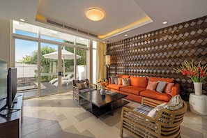 A modern living room with a large window, a sofa, a coffee table, and a TV. - Premier Village Da Nang by KayStay (Ngũ Hành Sơn)