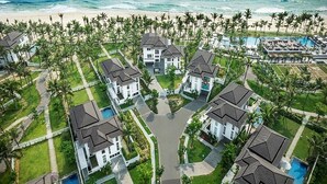 Vista aérea de un complejo turístico con varias casas, una piscina y una playa.