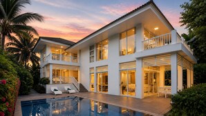 Una casa de dos pisos con piscina, balcones y jardín.