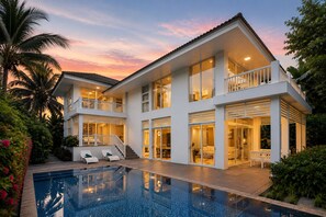 Une maison à deux étages avec une piscine, des balcons et un jardin.