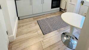 Una cocina moderna con armarios blancos, encimera negra, un fregadero y una pequeña mesa de comedor.