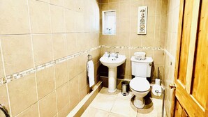 Un baño con inodoro, lavamanos y zona de ducha.