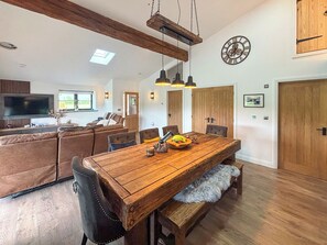 Uma área de refeições com mesa de madeira, bancos e luminária no teto.