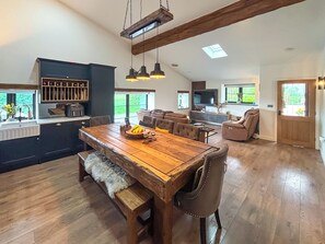 Amplia sala de estar con una mesa de comedor de madera, sofás de cuero y una cocina con armarios oscuros.