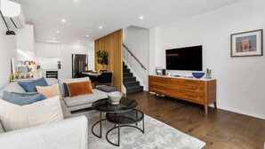 A modern living room with a sofa, coffee table, and a TV on a wooden cabinet. - Elegant Remuera 2BDR Retreat Prime Location (Auckland)