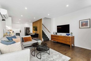 Una sala de estar moderna con un sofá, una mesa de centro y un televisor sobre un mueble de madera.