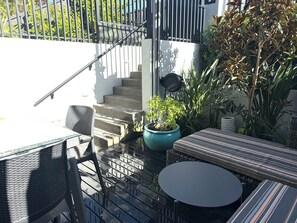 A patio area with outdoor furniture, a potted plant, and a staircase leading to an upper level. - Elegant Remuera 2BDR Retreat Prime Location (Auckland)