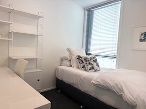 A bedroom with a bed, a desk, and a shelving unit. - Elegant Remuera 2BDR Retreat Prime Location (Auckland)