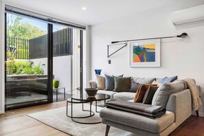 A modern living room with a sofa, a coffee table, and a painting on the wall. - Elegant Remuera 2BDR Retreat Prime Location (Auckland)