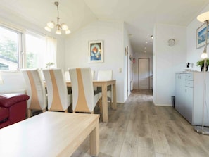 Ein moderner Essbereich mit Holztisch und -stühlen, eine Küche mit Schränken und ein Flur, der in einen anderen Raum führt.