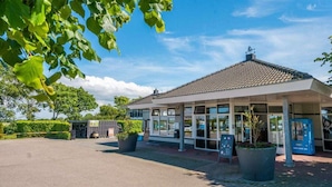 A building with a tiled roof, large windows, and potted plants. - Comfort 6 Persons (Egmond aan den Hoef)