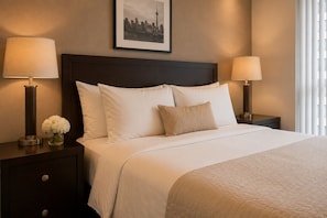 A hotel room with a large bed, two bedside tables, a nightstand, a framed cityscape picture, and a window with blinds. - Solenne Park Hotel (Toronto)