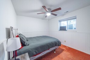 A bedroom with a bed, a ceiling fan, a window, and a radiator.