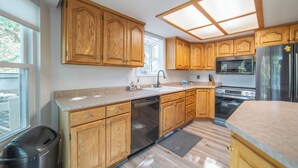 Une cuisine moderne avec des meubles en bois, des appareils électroménagers en acier inoxydable et une grande fenêtre.
