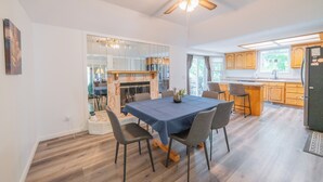 Une cuisine moderne avec des meubles en bois, un coin repas avec une nappe bleue et un ventilateur de plafond.