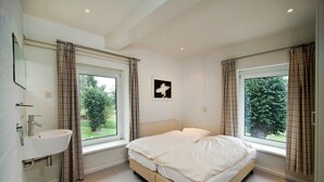Una camera da letto con un letto, una finestra, un lavandino e un quadro appeso al muro.