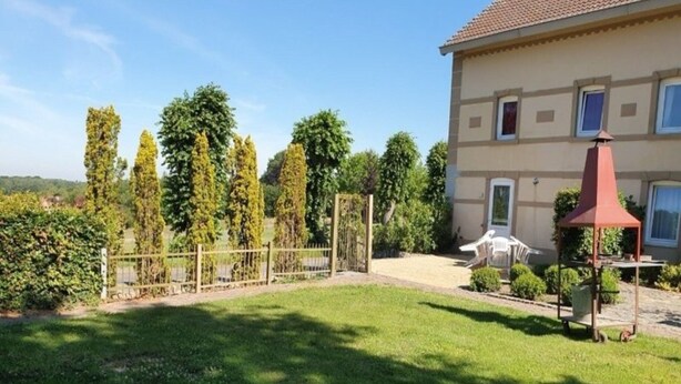 Una casa con un prato curato, un giardino recintato e un patio con mobili da esterno.