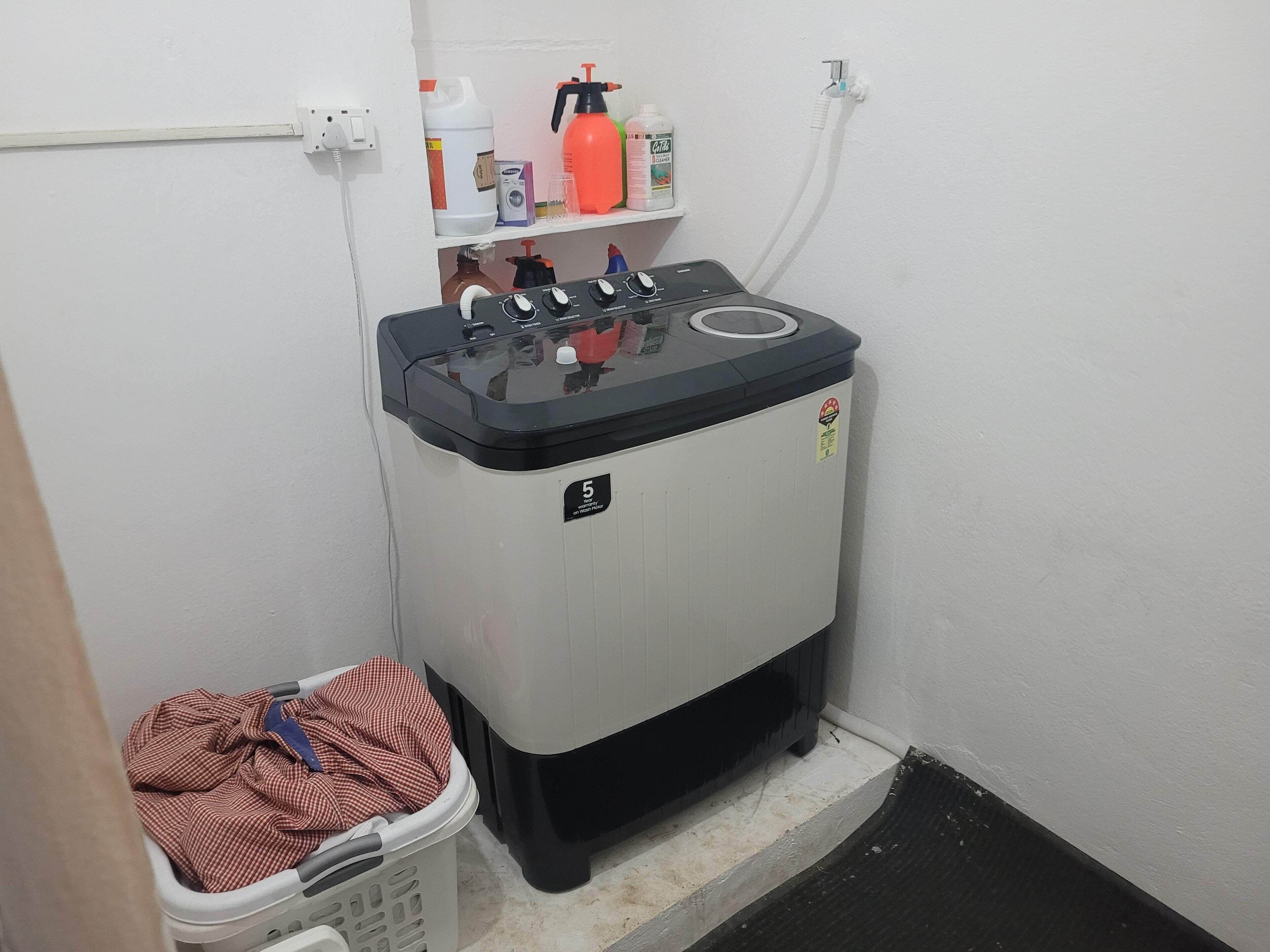 A compact laundry room with a washing machine, a drying machine, and a basket of clothes.