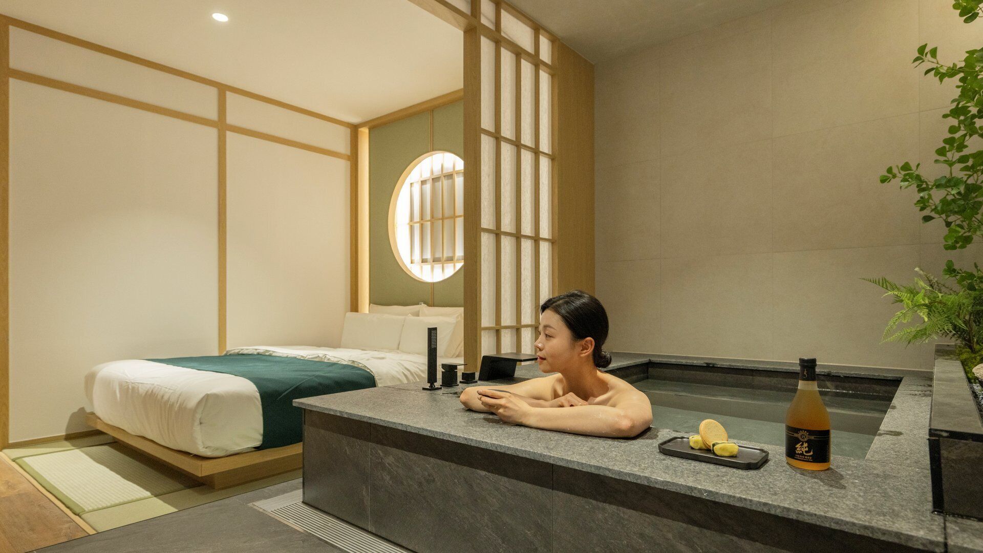Una habitación de hotel moderna con cama, un área de descanso con bebidas y aperitivos, y un ventanal con vistas.