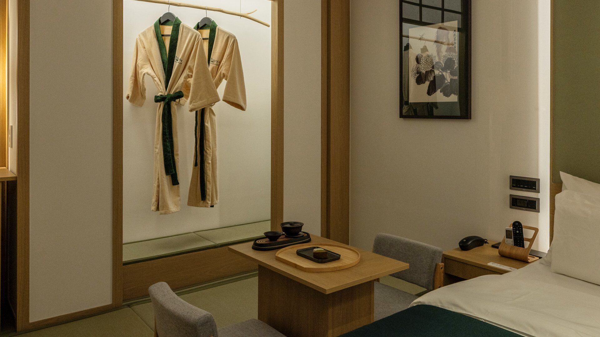 Une chambre d’hôtel comprenant un lit, un bureau avec un téléphone et une télécommande, une chaise et un téléviseur fixé au mur.