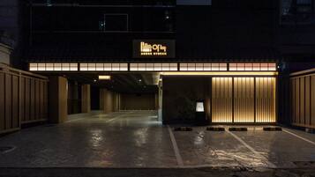 A parking garage entrance with a sign reading 'AnooK Ryokan' and a wooden structure with vertical slats.