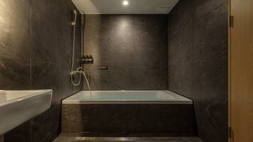 A modern bathroom with a bathtub, shower, and a sink.
