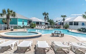 A pool area with lounge chairs and a hot tub, surrounded by houses with white roofs. - Charming Gulf Shores Cottage Beach Paradise for 10 Guests (Gulf Shores)