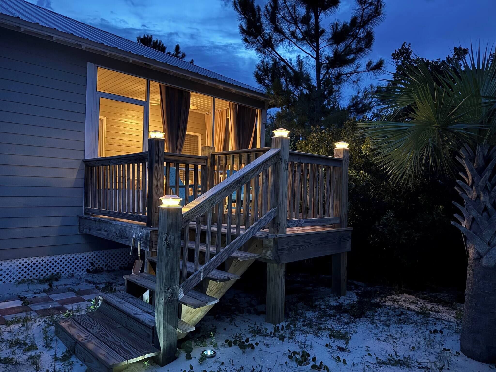 Eine Holzterrasse mit einer Treppe, die zu einem Haus mit großen Fenstern führt.